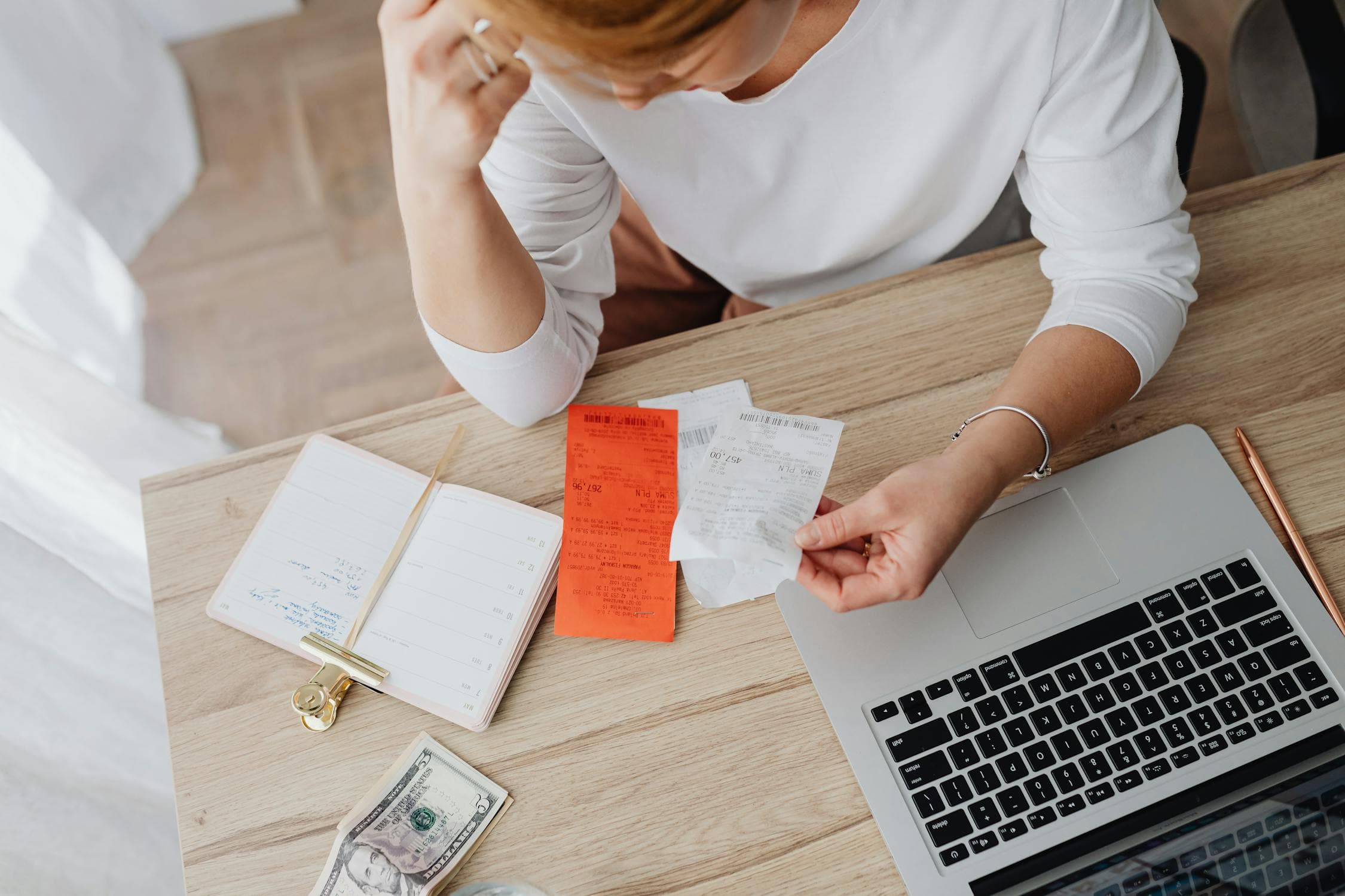 Freelancer sorting through receipts at a desk with a laptop